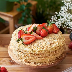 Napoleon cake with strawberries on a wooden background. Side view.