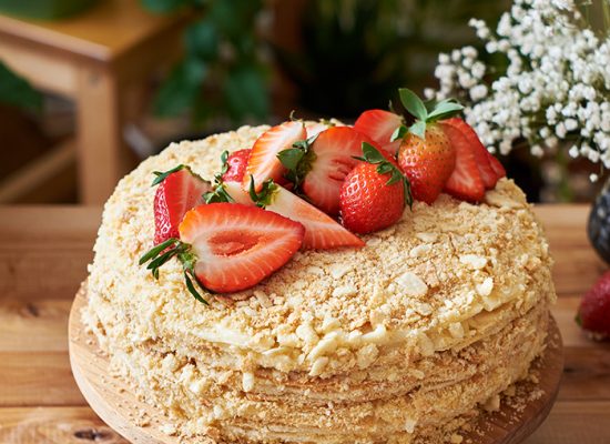 Napoleon cake with strawberries on a wooden background. Side view.